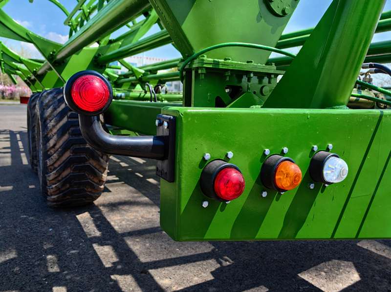 Close up view of the automated hydraulic pickup arm engaging a round bale