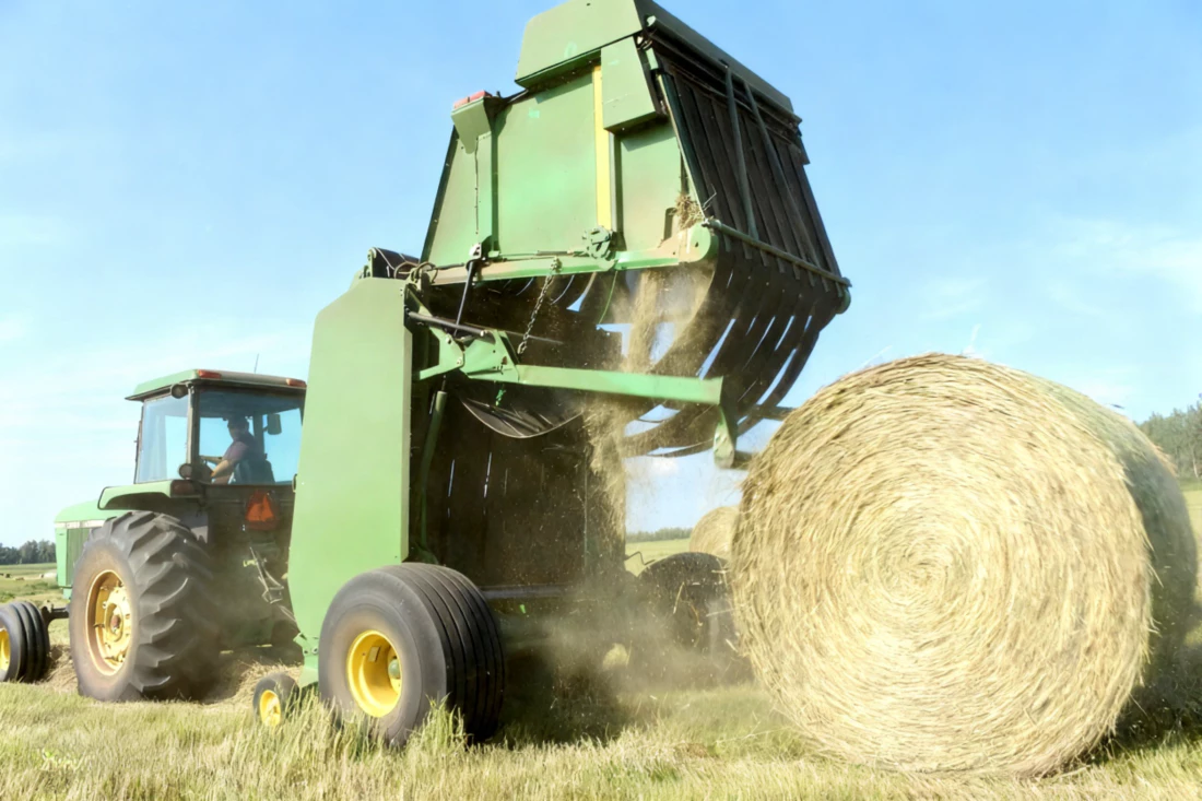 Round baler wrapping hay in a field